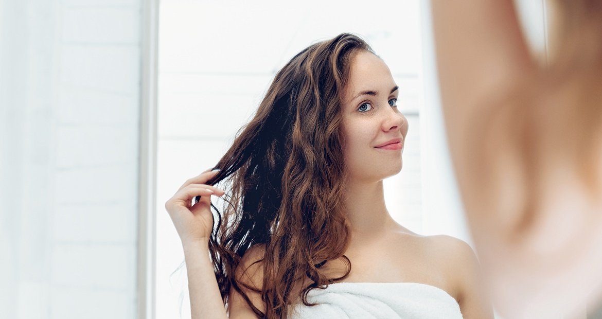 mulher de cabelo ondulado se olhando no espelho